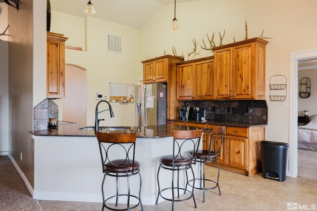 748 Thistle Dr, Spring Creek, NV 89815 - kitchen featuring stainless steel refrigerator with ice dispenser, a sink, a peninsula, tasteful backsplash, and dark stone countertops