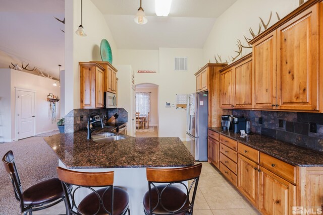 748 Thistle Dr, Spring Creek, NV 89815 - kitchen with appliances with stainless steel finishes, arched walkways, high vaulted ceiling, a sink, and tasteful backsplash
