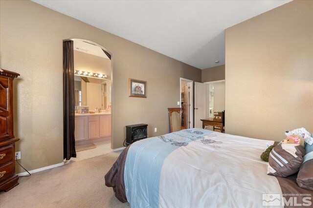 10010 Purple Sage Dr, Reno, NV 89506 - bedroom with light carpet, baseboards, a wood stove, ensuite bath, and arched walkways