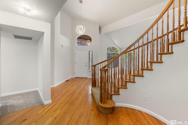foyer featuring baseboards, wood finished floors, stairway, and high vaulted ceiling