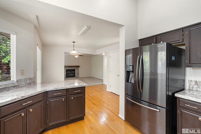 kitchen featuring stainless steel fridge with ice dispenser, light wood-style flooring, open floor plan, a peninsula, and a fireplace