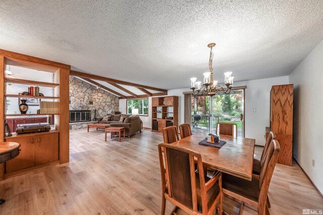 12565 Creek Crest Dr, Reno, NV 89511 - dining space featuring light wood-type flooring, a textured ceiling, a chandelier, vaulted ceiling, and a stone fireplace