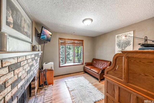 12565 Creek Crest Dr, Reno, NV 89511 - sitting room featuring a brick fireplace, a textured ceiling, and light wood finished floors