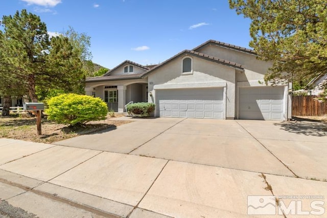 5979 Hidden Highlands Dr, Reno, NV 89502 - view of front facade featuring a garage, concrete driveway, stucco siding, and fence