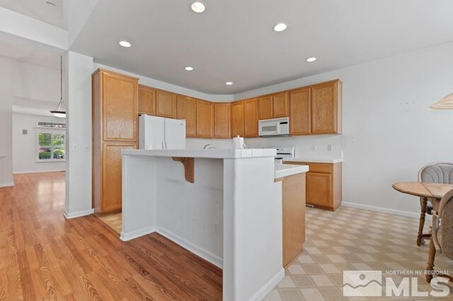 5979 Hidden Highlands Dr, Reno, NV 89502 - kitchen featuring white appliances, light countertops, a center island with sink, recessed lighting, and baseboards