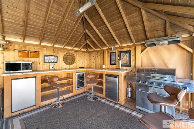 9185 Raytheon Ct, Reno, NV 89506 - bar area with stainless steel microwave, fridge, wood walls, wood ceiling, and beamed ceiling