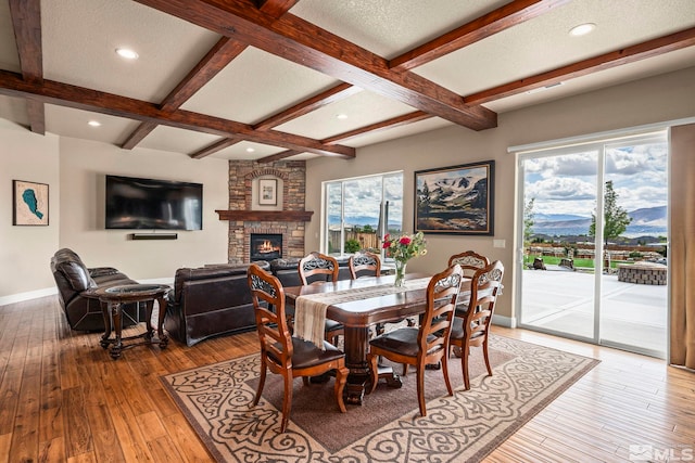 9825 Hayfield Dr, Sparks, NV 89441 - dining space with baseboards, a stone fireplace, light wood-type flooring, beam ceiling, and a mountain view
