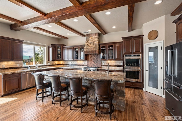 9825 Hayfield Dr, Sparks, NV 89441 - kitchen with stainless steel appliances, an island with sink, a kitchen bar, beam ceiling, and backsplash