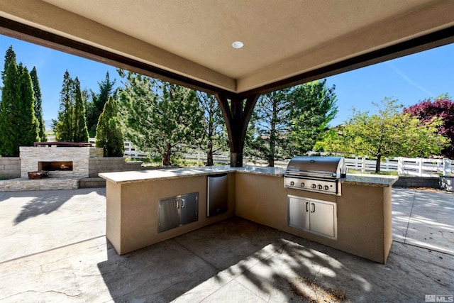 11115 Boulder Glen Way, Reno, NV 89511 - view of patio / terrace with grilling area, an outdoor kitchen, fence, and an outdoor stone fireplace