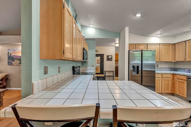 5190 Orinda Dr, Sparks, NV 89436 - kitchen featuring stainless steel appliances, tile counters, a peninsula, light wood-style flooring, and lofted ceiling