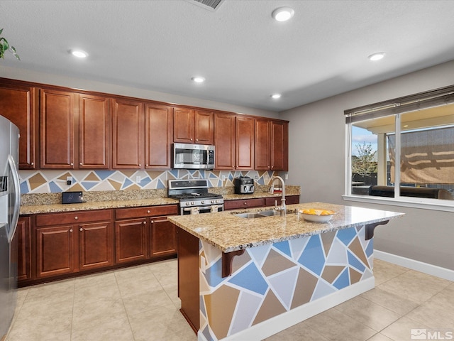 2401 Bridgetown Loop, Sparks, NV 89436 - kitchen featuring appliances with stainless steel finishes, a sink, light stone countertops, decorative backsplash, and an island with sink