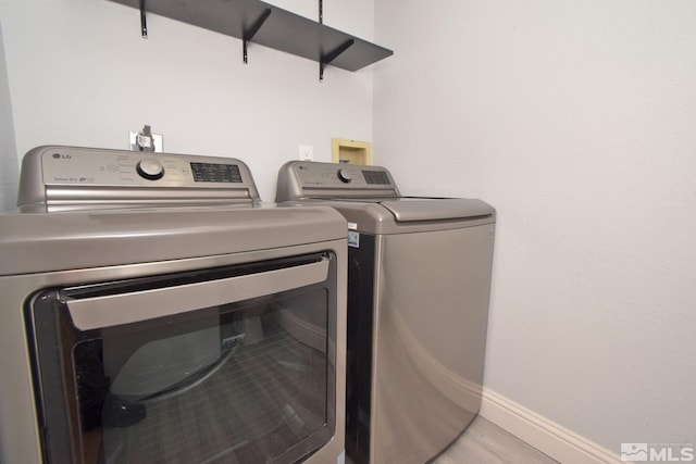laundry area with independent washer and dryer, baseboards, and light wood-style flooring