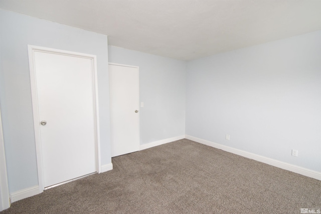 unfurnished bedroom featuring dark colored carpet and baseboards