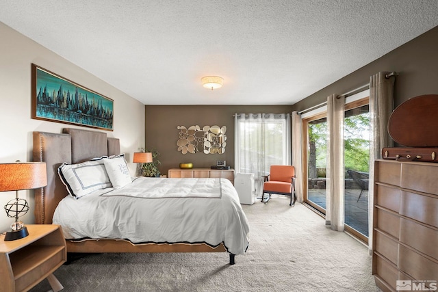 bedroom with access to exterior, carpet floors, and a textured ceiling