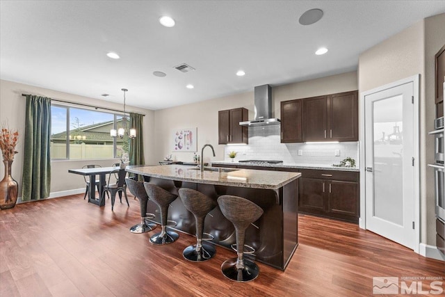11129 Bandero Heights Ln, Reno, NV 89521 - kitchen with wall chimney range hood, stainless steel appliances, a sink, a kitchen breakfast bar, and light stone countertops