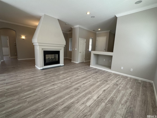 10599 Crystal Bay Dr, Reno, NV 89521 - unfurnished living room featuring wood finished floors, baseboards, crown molding, arched walkways, and a large fireplace