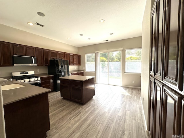 10599 Crystal Bay Dr, Reno, NV 89521 - kitchen with stainless steel appliances, a sink, light wood finished floors, a kitchen island, and dark brown cabinetry