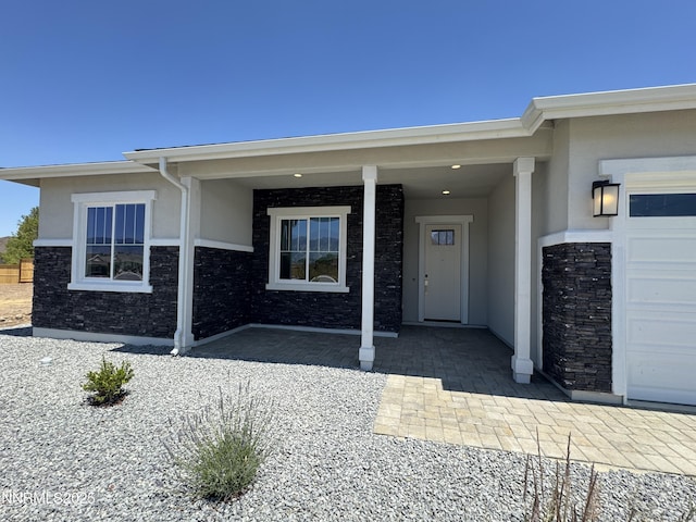 638 Sage Grouse Lp, Gardnerville, NV 89460 - view of exterior entry with stucco siding, a garage, and stone siding