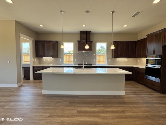638 Sage Grouse Lp, Gardnerville, NV 89460 - kitchen with stainless steel double oven, a kitchen island with sink, dark brown cabinets, tasteful backsplash, and recessed lighting