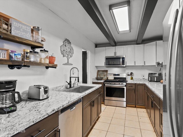 665 Southworth Dr, Reno, NV 89512 - kitchen with stainless steel appliances, a sink, light tile patterned floors, beam ceiling, and white cabinetry