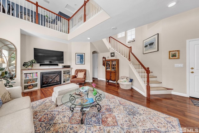 2374 Roman Dr, Sparks, NV 89434 - living room with a high ceiling, arched walkways, stairway, wood finished floors, and a glass covered fireplace