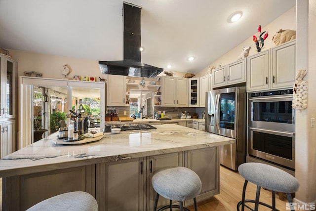 6525 Monticello Ct, Reno, NV 89519 - kitchen featuring appliances with stainless steel finishes, island range hood, a kitchen breakfast bar, a center island, and light wood-style floors