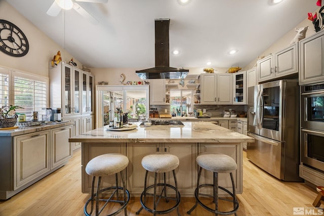 6525 Monticello Ct, Reno, NV 89519 - kitchen featuring appliances with stainless steel finishes, island exhaust hood, a kitchen island, a breakfast bar, and lofted ceiling