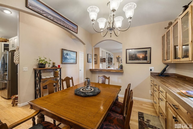 6525 Monticello Ct, Reno, NV 89519 - dining space featuring light wood finished floors, arched walkways, a chandelier, and baseboards