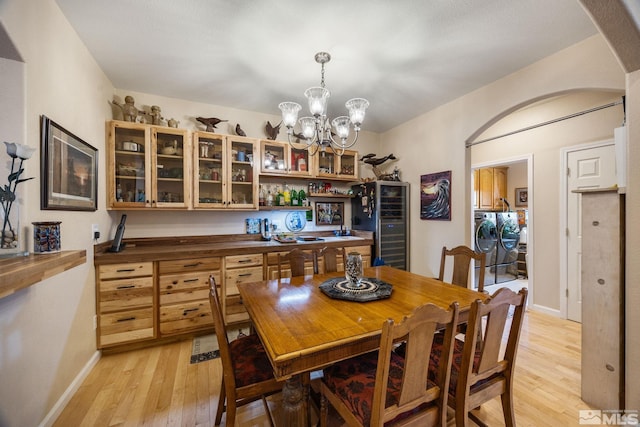 6525 Monticello Ct, Reno, NV 89519 - dining space with washing machine and clothes dryer, light wood-style floors, arched walkways, a chandelier, and beverage cooler
