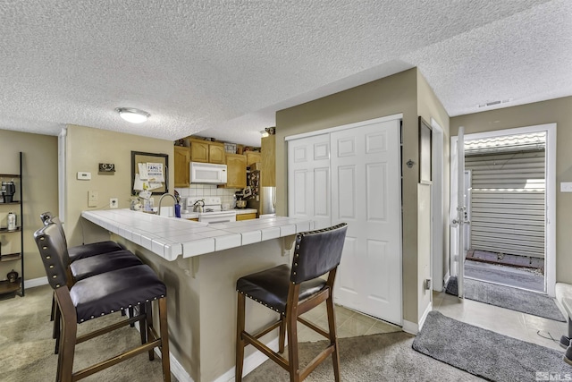 1064 Bradley Sq, Sparks, NV 89434 - kitchen with white appliances, tile counters, a breakfast bar area, a peninsula, and light carpet
