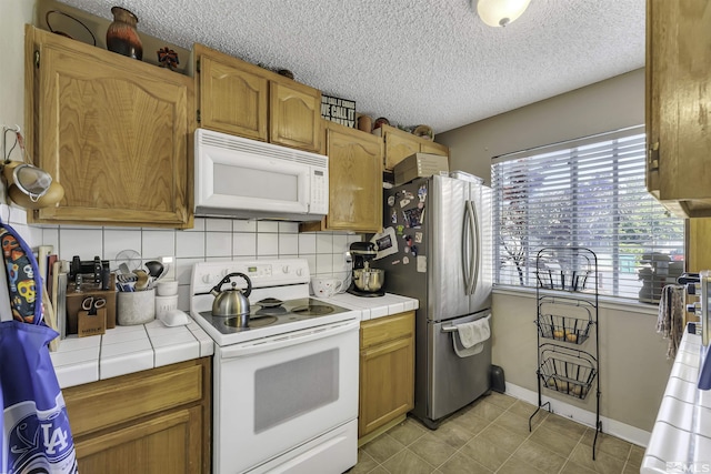 1064 Bradley Sq, Sparks, NV 89434 - kitchen featuring white appliances, tile countertops, decorative backsplash, a textured ceiling, and baseboards