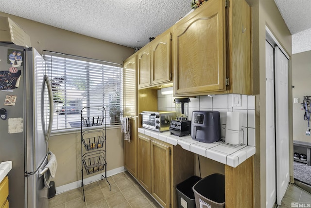1064 Bradley Sq, Sparks, NV 89434 - kitchen featuring freestanding refrigerator, tile counters, a textured ceiling, baseboards, and light tile patterned floors