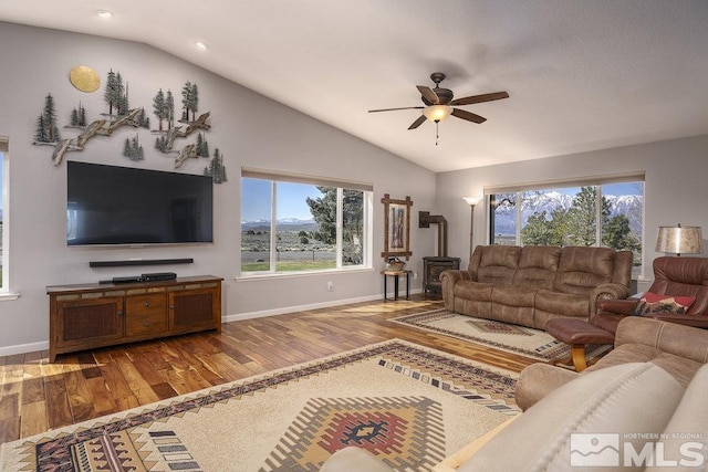 1051 Tenabo Ln, Gardnerville, NV 89410 - living room featuring vaulted ceiling, hardwood / wood-style flooring, a wood stove, healthy amount of natural light, and baseboards