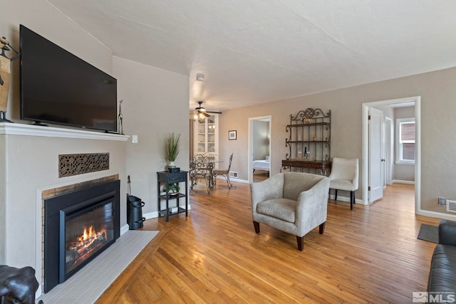 2066 Plumas St, Reno, NV 89509 - living room featuring a glass covered fireplace, light wood finished floors, a ceiling fan, and baseboards