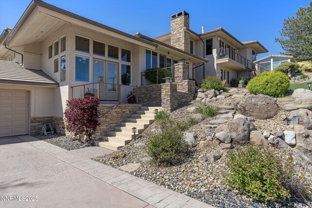 10286 Morning Song Trl, Reno, NV 89511 - view of front of property featuring stone siding, a chimney, stairs, driveway, and french doors