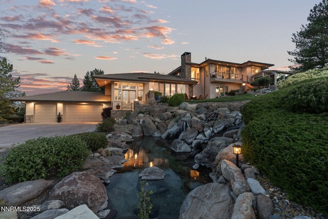 10286 Morning Song Trl, Reno, NV 89511 - view of front of home featuring stone siding, a chimney, driveway, an attached garage, and stucco siding