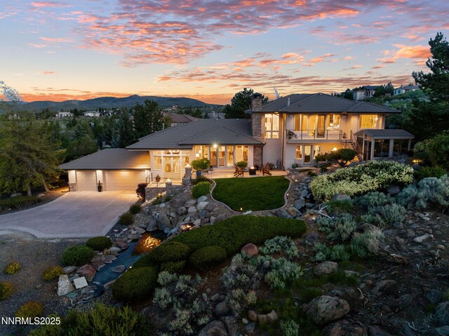10286 Morning Song Trl, Reno, NV 89511 - view of front of house with a balcony, a chimney, a garage, concrete driveway, and a mountain view