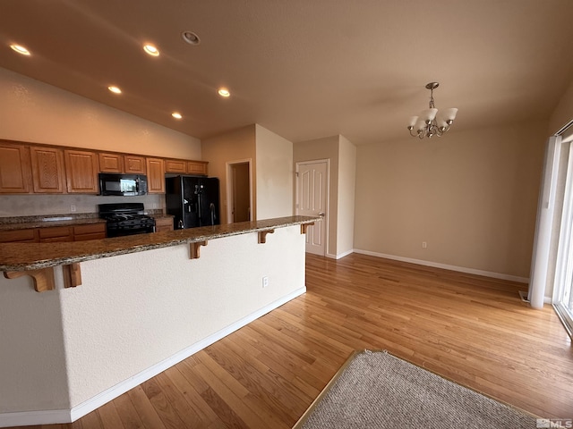 5740 Sarah Rd, Fallon, NV 89406 - kitchen with black appliances, a kitchen bar, light wood finished floors, a chandelier, and recessed lighting