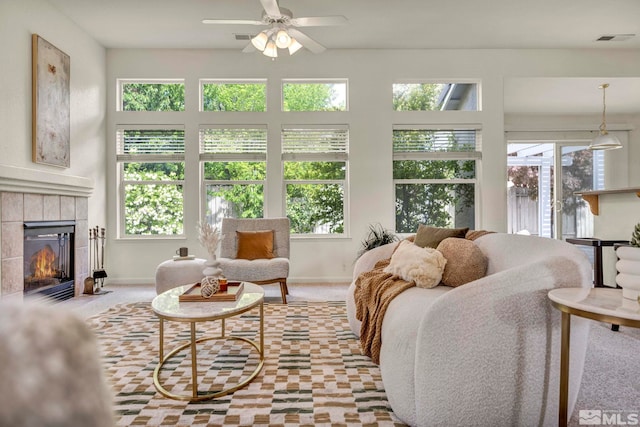 living area featuring healthy amount of natural light, a ceiling fan, a fireplace, and baseboards