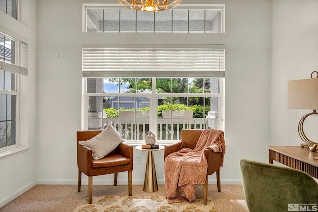 living area featuring carpet floors, baseboards, and a chandelier