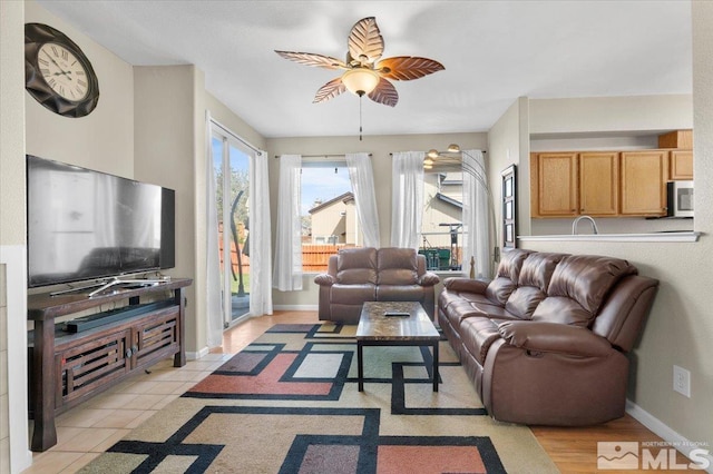 living area featuring a ceiling fan and baseboards