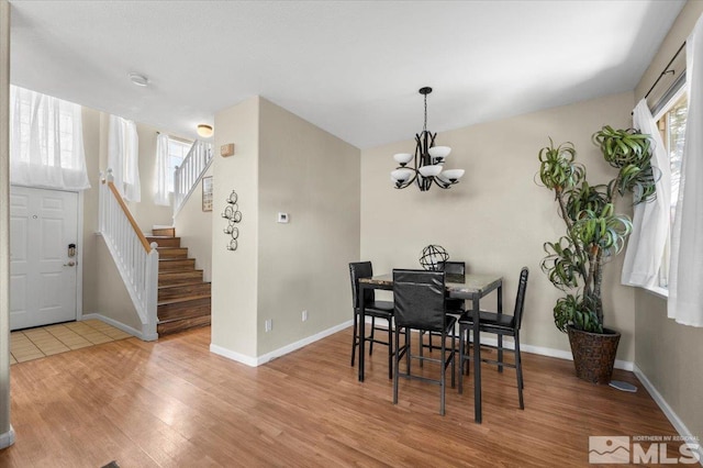 dining area with wood finished floors, a chandelier, baseboards, and stairway