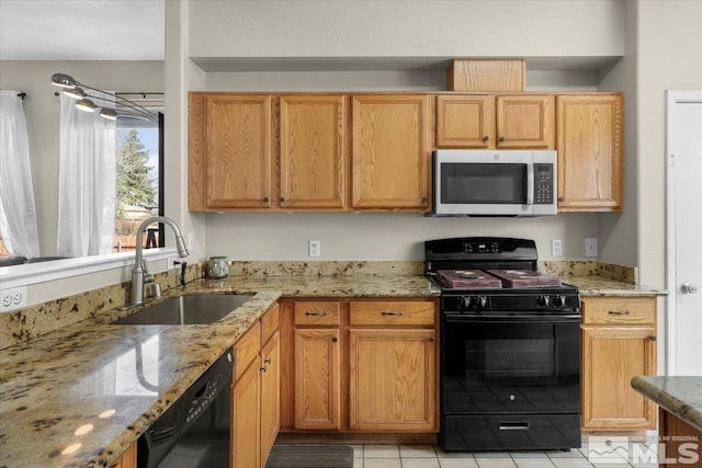 kitchen featuring black appliances, a sink, light tile patterned floors, and light stone counters