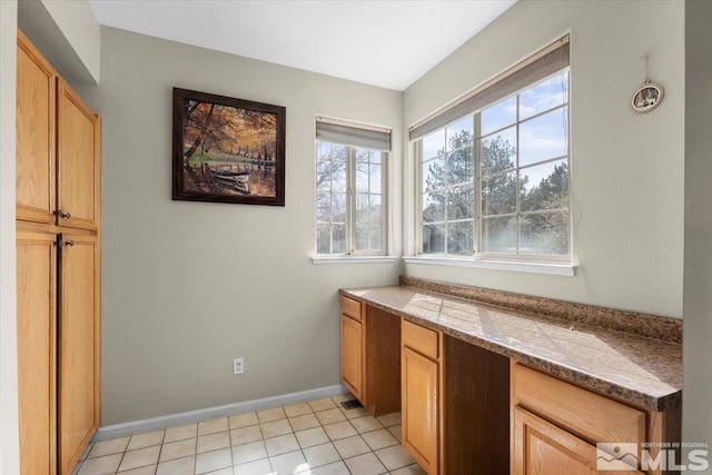 unfurnished office featuring baseboards and light tile patterned floors