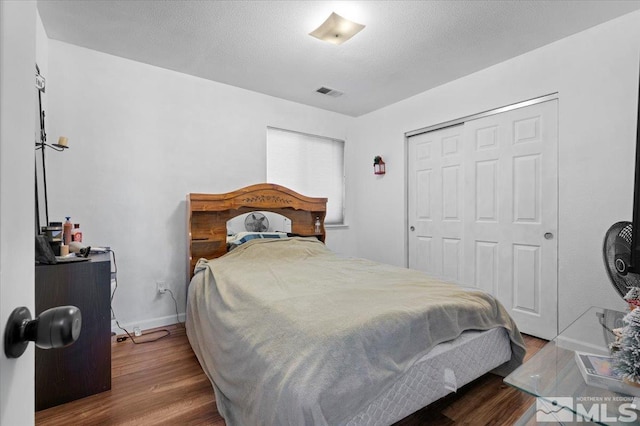 bedroom with wood finished floors and a closet