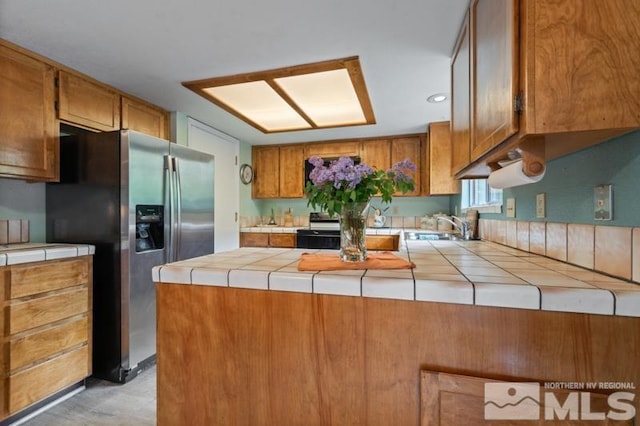 1940 Peavine Rd, Reno, NV 89503 - kitchen featuring stainless steel fridge, tile counters, a peninsula, brown cabinets, and a sink