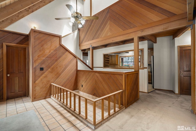 staircase with wooden walls, a ceiling fan, and carpet flooring