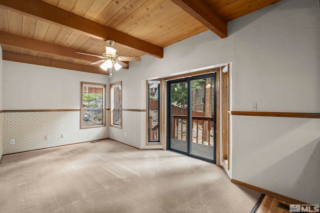 empty room featuring plenty of natural light, wooden ceiling, beam ceiling, carpet flooring, and ceiling fan