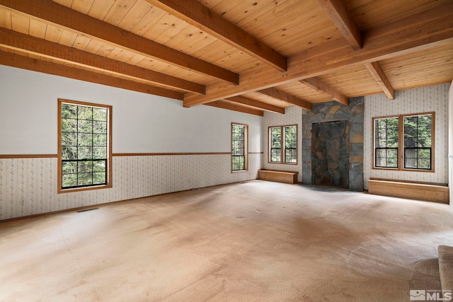 unfurnished living room featuring wallpapered walls, wainscoting, plenty of natural light, wooden ceiling, and carpet