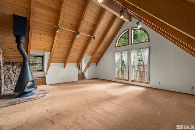 unfurnished living room with carpet floors, beamed ceiling, wood ceiling, a wood stove, and high vaulted ceiling